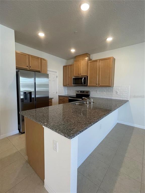 12264 Linear Street Orlando, FL 32832 - Photo 4 of 10 a kitchen with stainless steel appliances granite countertop a sink a stove and a refrigerator
