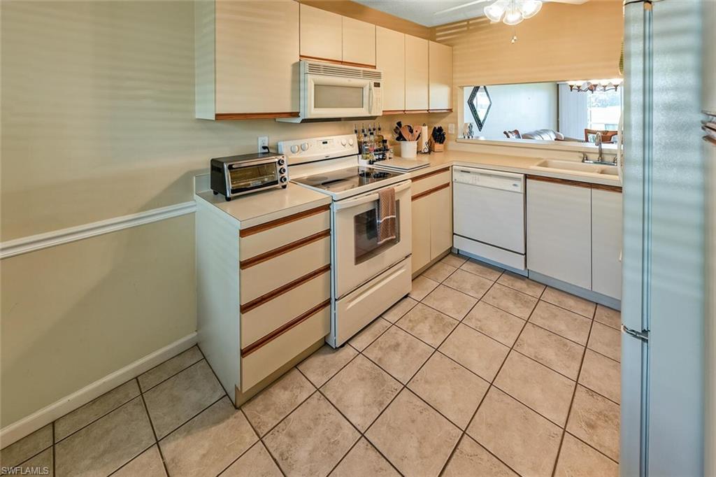 780 Augusta Boulevard, Unit C102 Naples, FL 34113 - Photo 11 of 26 a kitchen with a stove cabinets and a sink