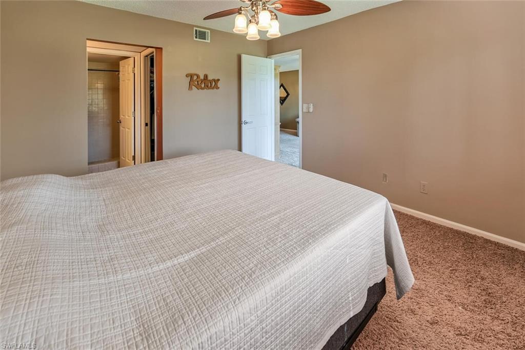 780 Augusta Boulevard, Unit C102 Naples, FL 34113 - Photo 14 of 26 a bedroom with a bed and a chandelier