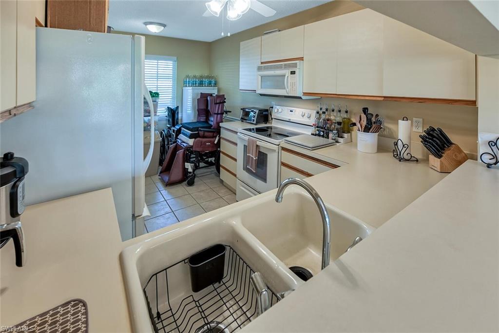 780 Augusta Boulevard, Unit C102 Naples, FL 34113 - Photo 10 of 26 a kitchen with a sink a stove and a refrigerator