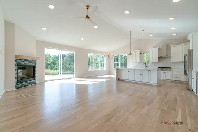a view of an empty room with wooden floor and a kitchen