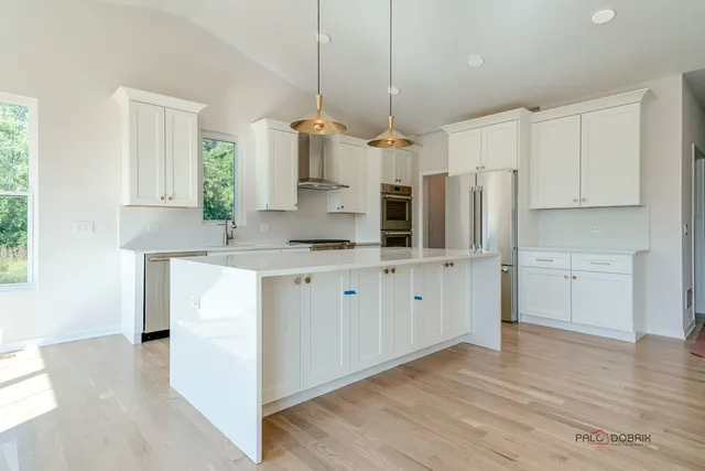 a kitchen with stainless steel appliances kitchen island granite countertop a refrigerator and a sink
