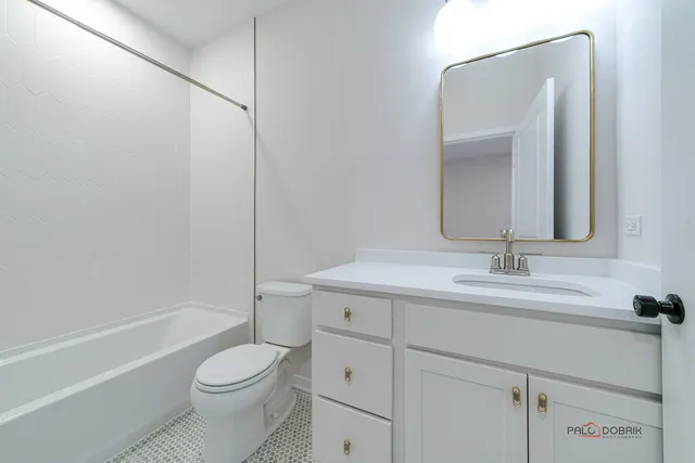 a bathroom with a toilet a sink a mirror a bathtub and vanity