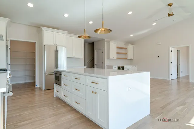 a large kitchen with a large counter top a sink stainless steel appliances and cabinets