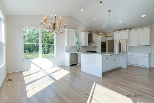 a large kitchen with stainless steel appliances kitchen island granite countertop a stove a sink dishwasher and a large refrigerator with wooden floor