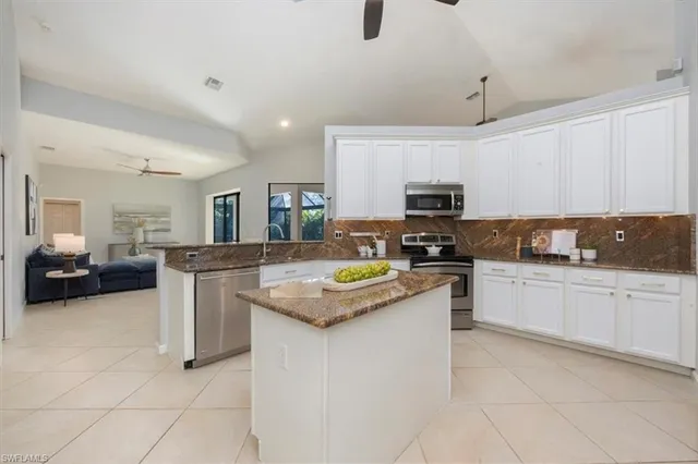 a kitchen with granite countertop a sink a counter top space appliances and cabinets
