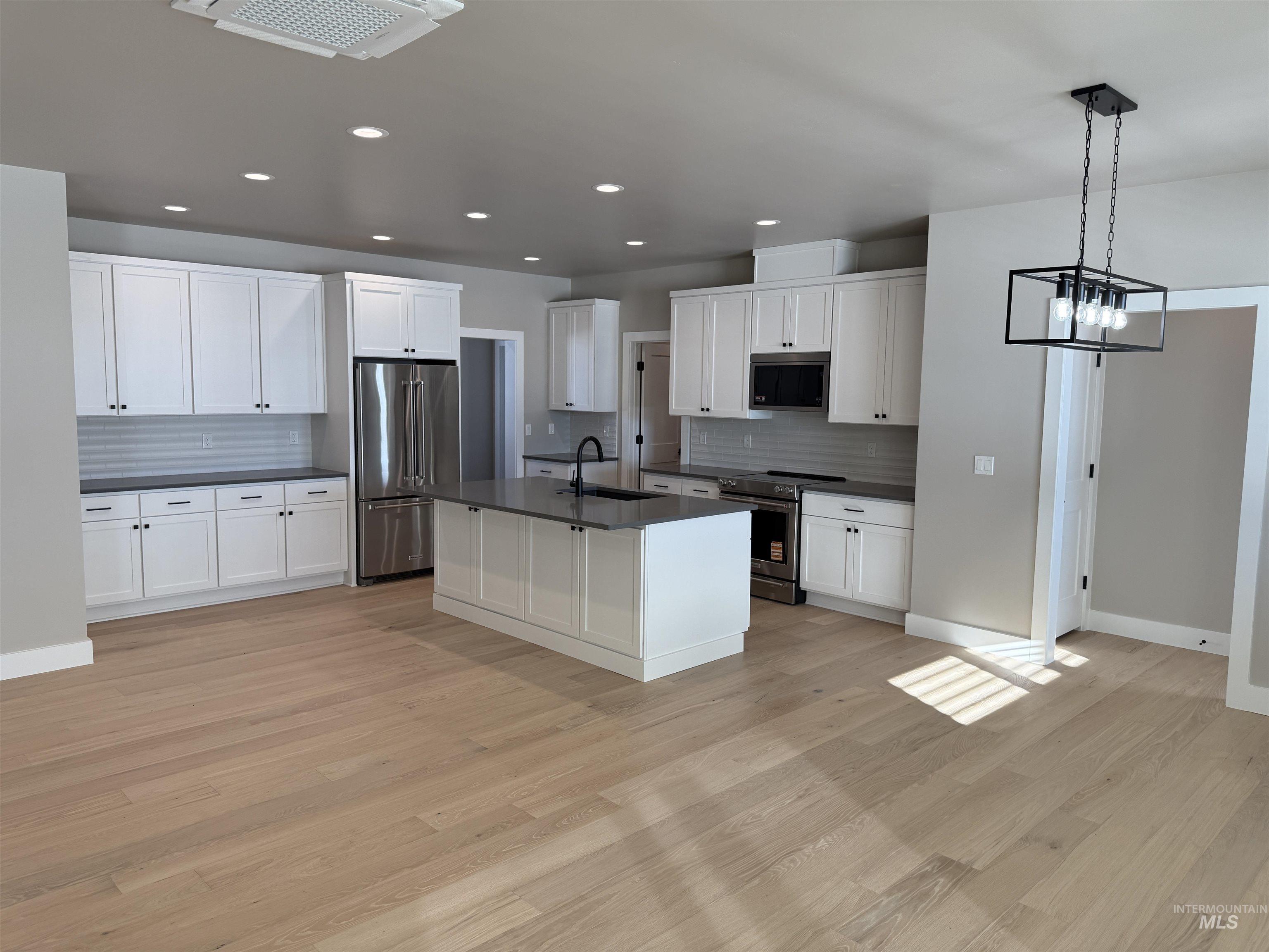 14059 Mulberry McCall, ID 83638 - Photo 5 of 32 Kitchen featuring stainless steel appliances, dark countertops, an island with sink, white cabinets, and recessed lighting