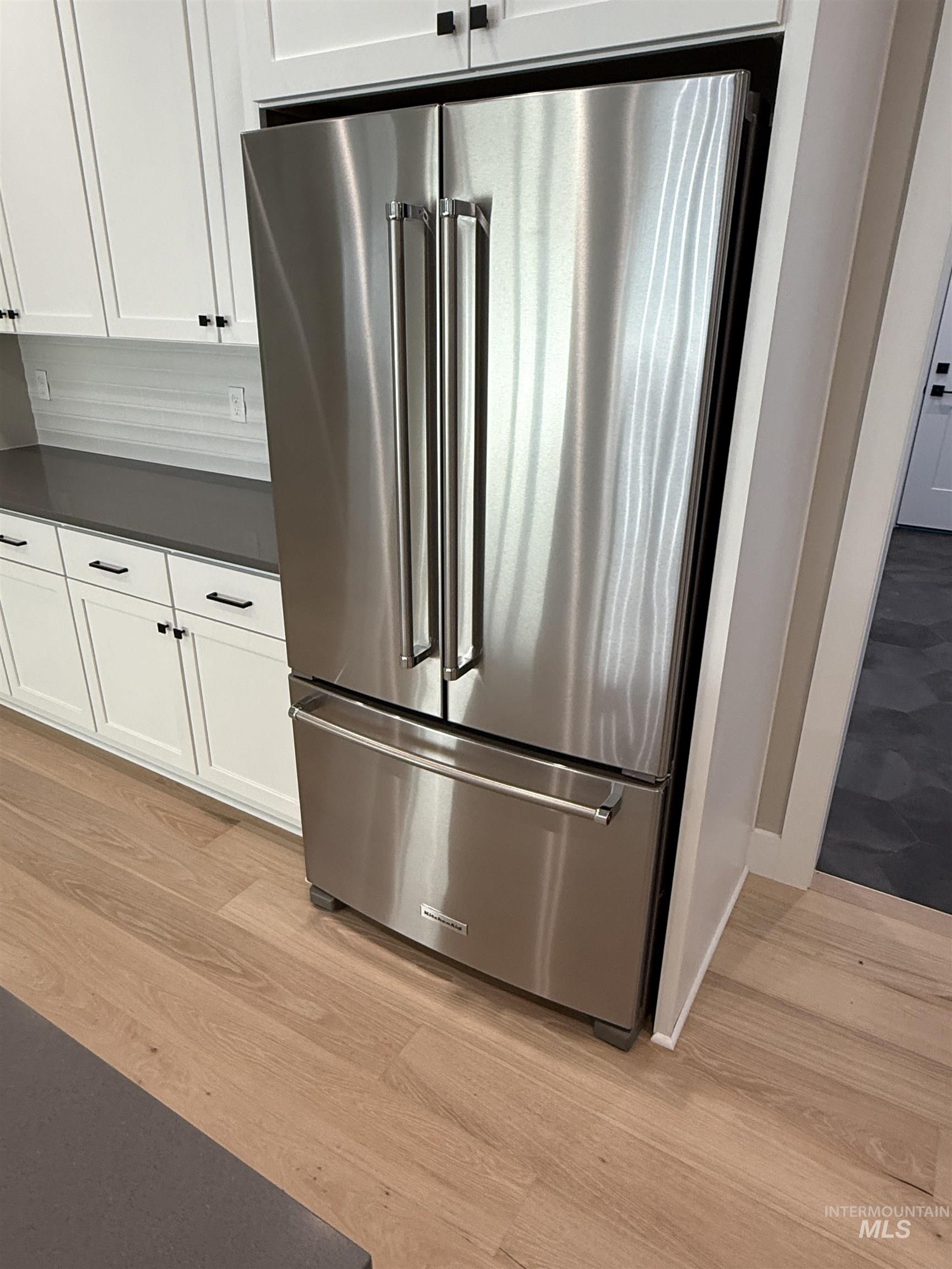 14059 Mulberry McCall, ID 83638 - Photo 7 of 32 Kitchen view of dark countertops, high end refrigerator, white cabinets, and light wood-type flooring