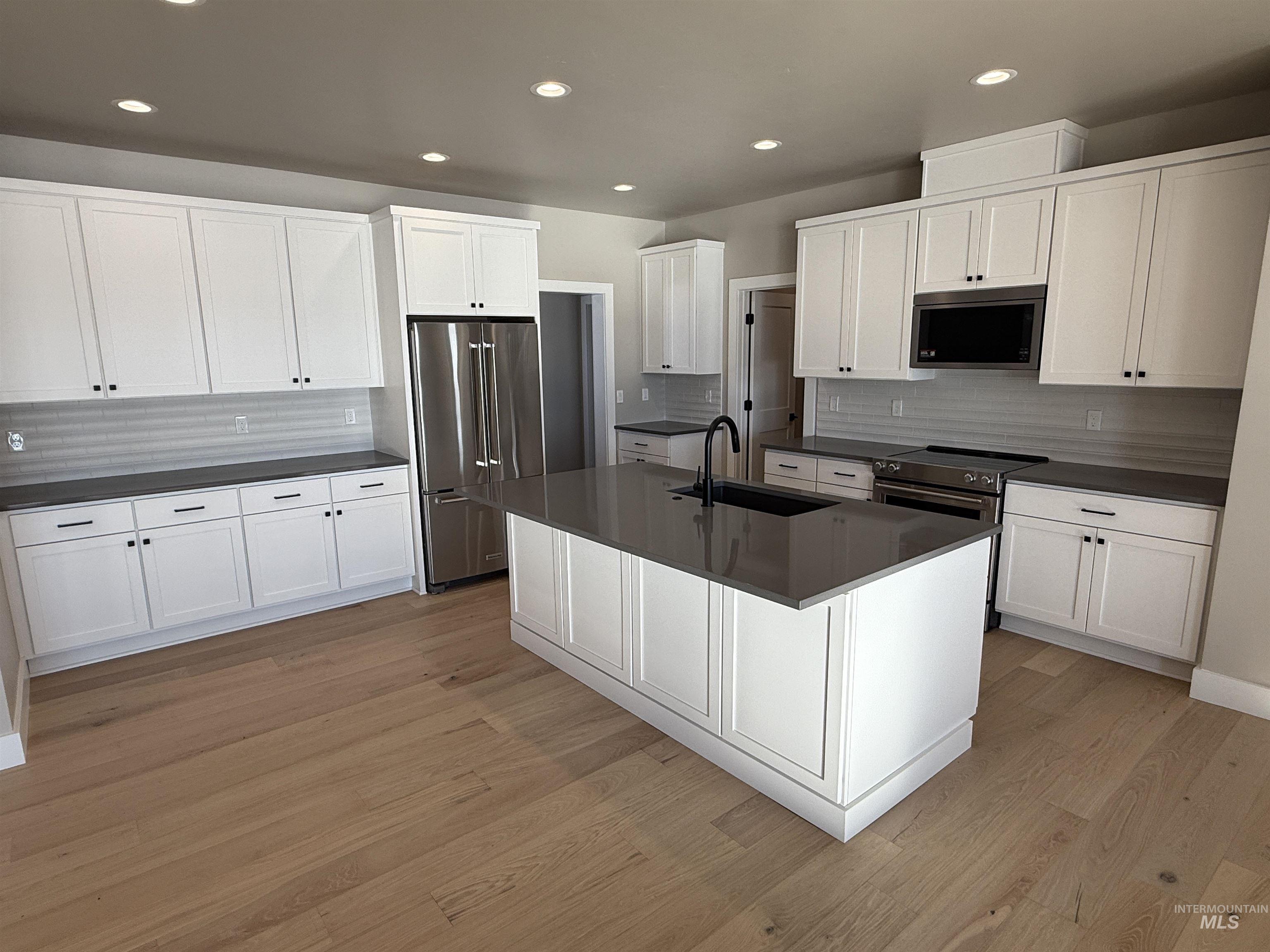 14059 Mulberry McCall, ID 83638 - Photo 9 of 32 Kitchen with appliances with stainless steel finishes, white cabinets, an island with sink, tasteful backsplash, and recessed lighting