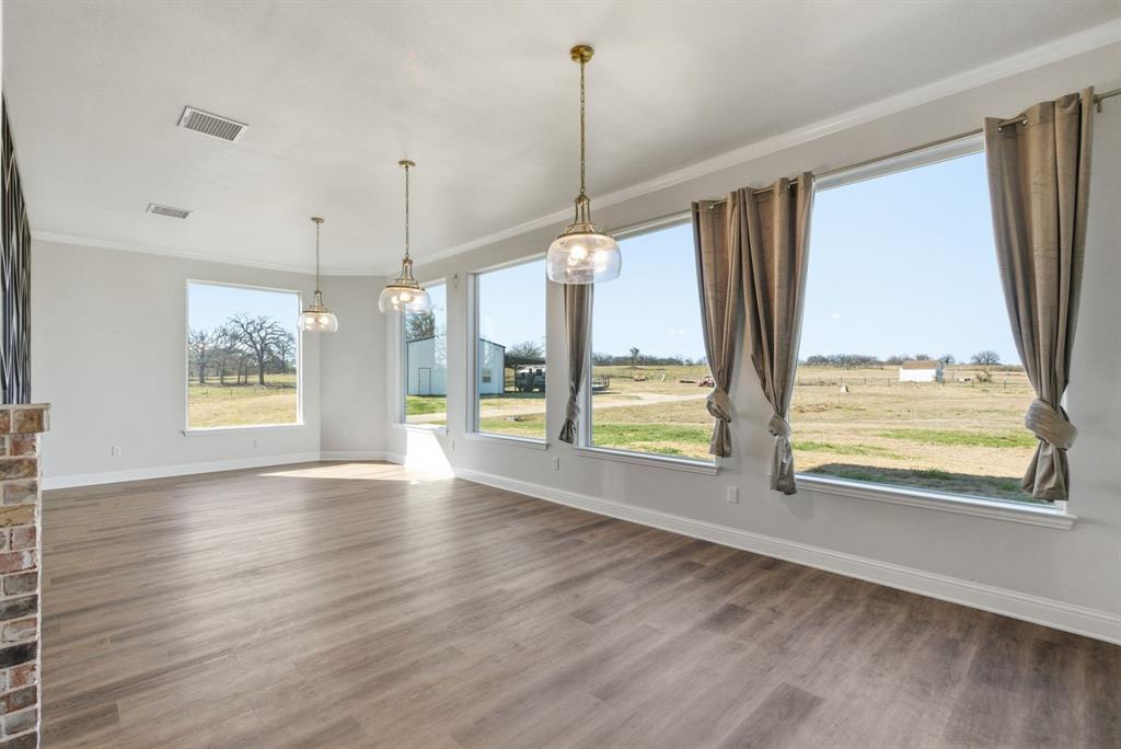 4600 Old Brock Road Weatherford, TX 76087 - Photo 15 of 37 Expansive room featuring wood-finish flooring, a brick accent wall, and multiple large windows with white trim