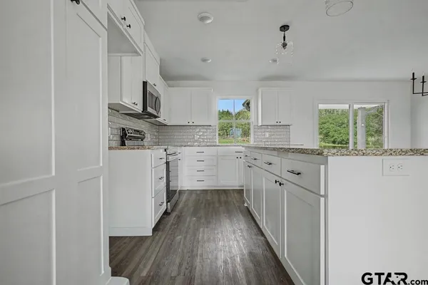 a kitchen with cabinets stainless steel appliances a sink and a window