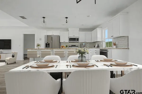 a kitchen with stainless steel appliances a sink a stove a refrigerator and white cabinets