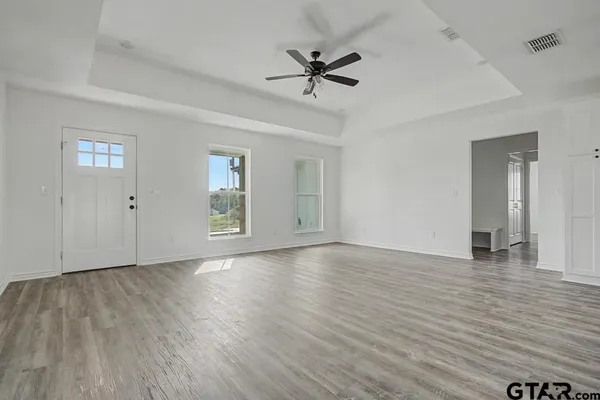 a view of an empty room with a window and wooden floor