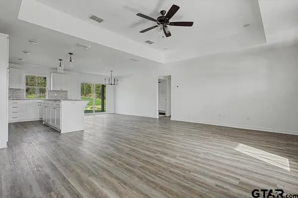 a view of a big room with wooden floor and a kitchen space