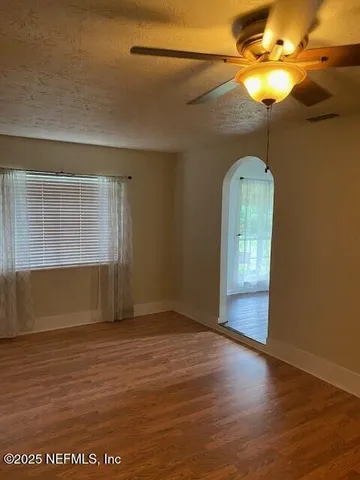 a view of an empty room with a window and wooden floor