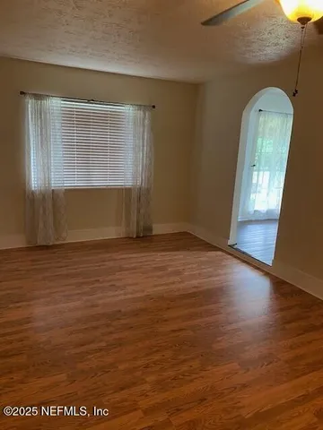 an empty room with wooden floor and windows