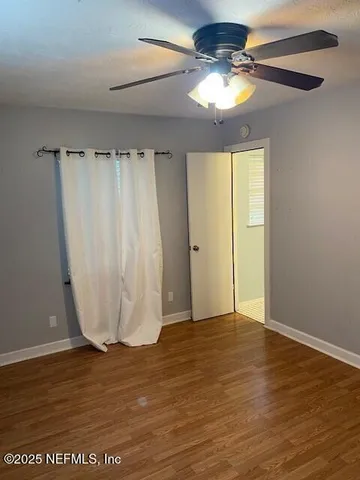 a view of a room with wooden floor and a ceiling fan