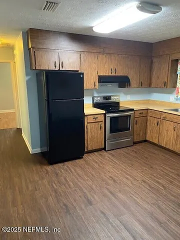 a kitchen with granite countertop wooden cabinets and a refrigerator