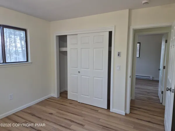 a view of empty room with wooden floor and fan
