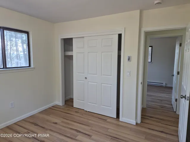 a view of empty room with wooden floor and fan