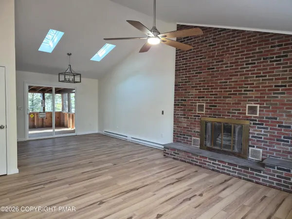 a view of an empty room with wooden floor and a fireplace