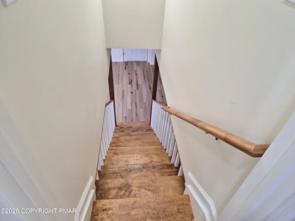 an empty room with wooden floor fireplace and windows