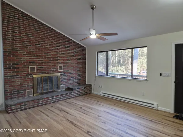 a view of wooden floor fire place and windows in a room