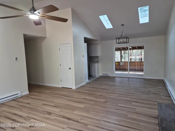 a view of an empty room with window and wooden floor