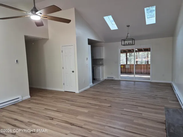 a view of an empty room with window and wooden floor