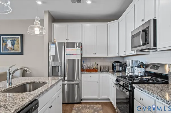 a kitchen with stainless steel appliances granite countertop a sink stove and refrigerator