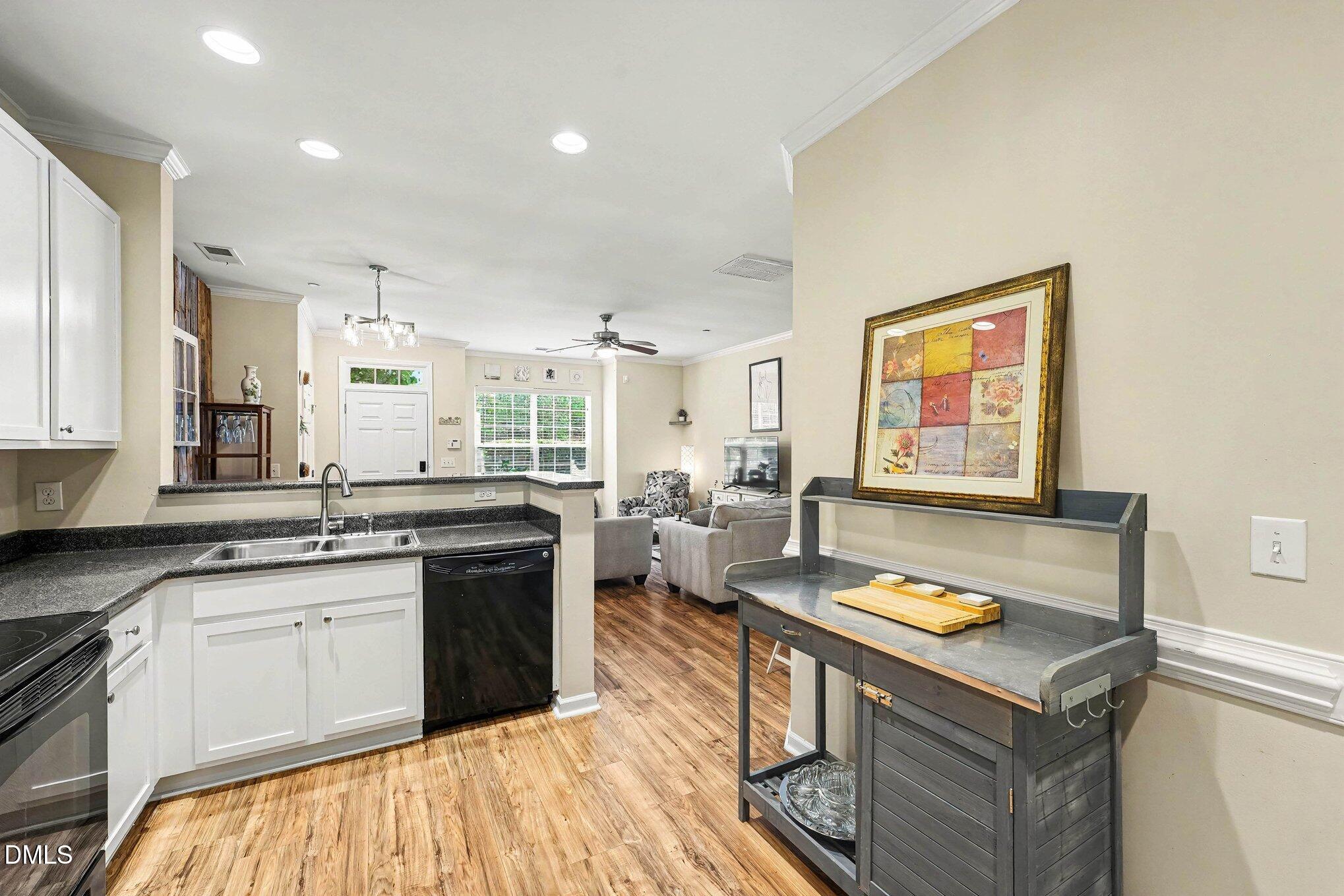 1130 Renewal Place, Unit 106 Raleigh, NC 27603 - Photo 11 of 34 a kitchen with a stove a sink dishwasher and a microwave oven with white countertops