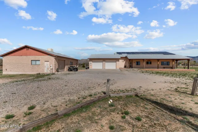a front view of a house with a dirt yard and a large tree