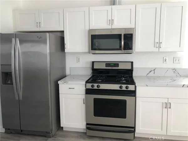 a kitchen with stainless steel appliances granite countertop a stove a microwave and white cabinets