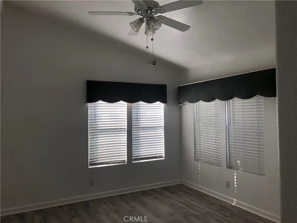 an empty room with wooden floor fireplace and windows