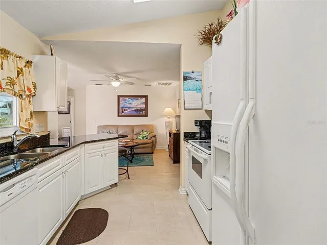 a kitchen with stainless steel appliances granite countertop a dining table chairs and a refrigerator