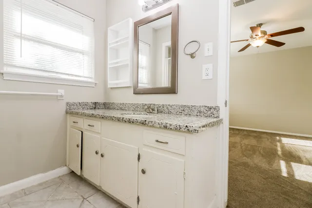 a bathroom with a granite countertop sink and a mirror