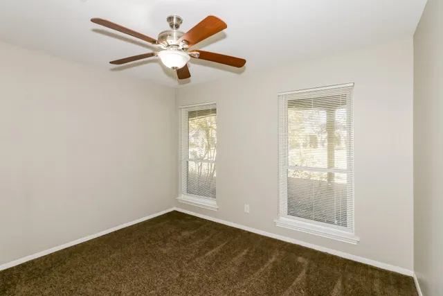 an empty room with windows and fan