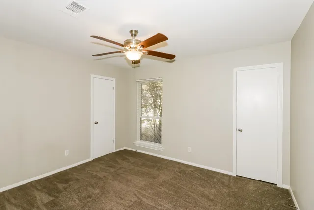 an empty room with windows and fan