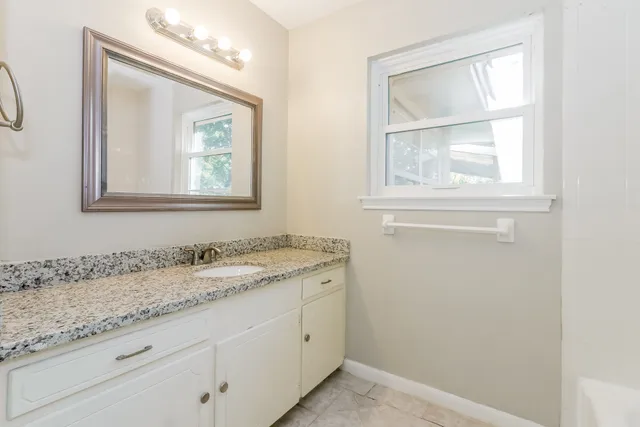 a bathroom with a granite countertop sink a vanity and a window