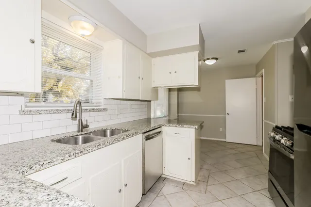 a kitchen with granite countertop a sink stainless steel appliances and cabinets