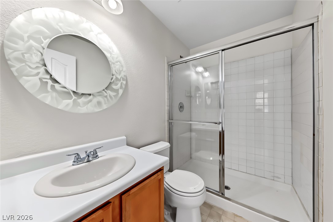 205 Genesee Point Street Henderson, NV 89074 - Photo 17 of 30 A classic walk-in shower features glass sliding doors and white tiled walls.