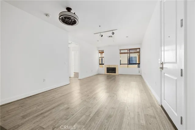 a view of an empty room with a window and wooden floor