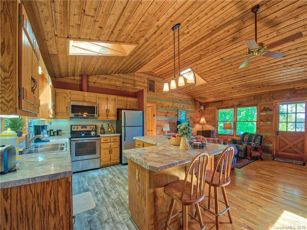 949 Setzercove Road Maggie Valley, NC 28751 - Photo 18 of 31 a kitchen with stainless steel appliances kitchen island granite countertop a table chairs and a wooden floor