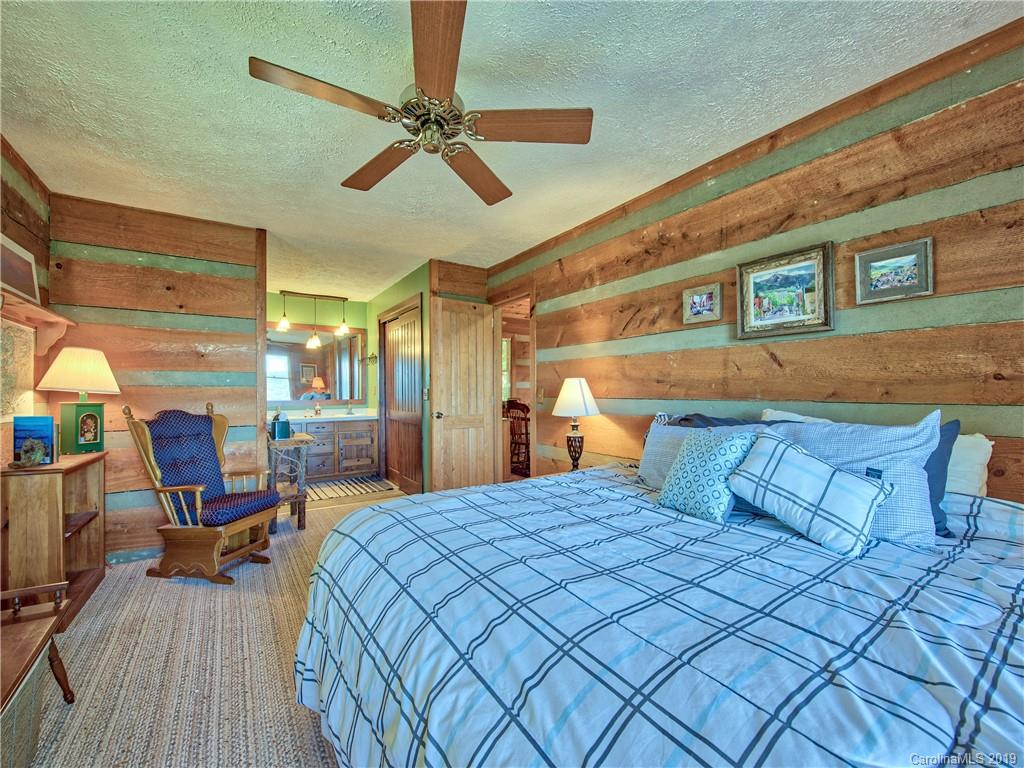 949 Setzercove Road Maggie Valley, NC 28751 - Photo 22 of 31 a bedroom with a bed a desk and chair with wooden floor