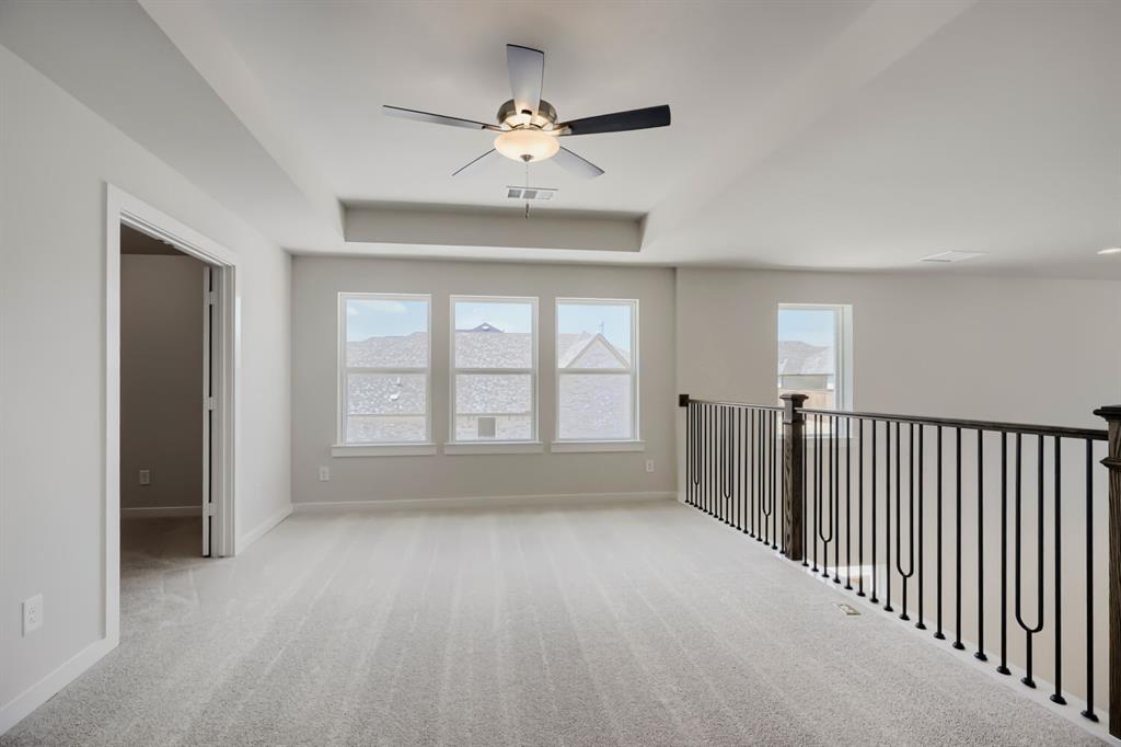 4407 Windy Point Road Oak Point, TX 75068 - Photo 2 of 27 Spacious upper-level room featuring light gray carpeting, a tray ceiling, and a ceiling fan with light fixture