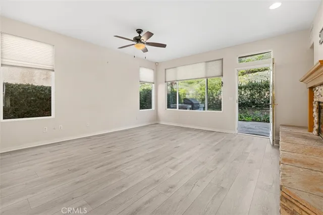 a view of an empty room with wooden floor fireplace and a window