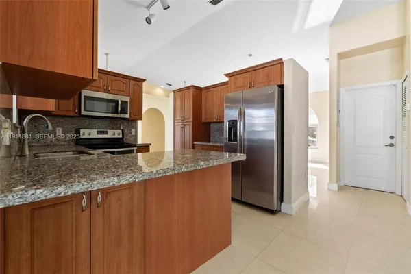 a kitchen with stainless steel appliances granite countertop a refrigerator and a sink