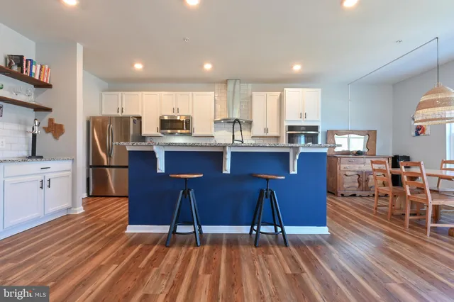 a kitchen with stainless steel appliances a dining table chairs and wooden floor