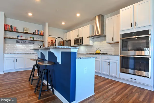 a kitchen with stainless steel appliances granite countertop a stove top oven a sink dishwasher and cabinets with wooden floor