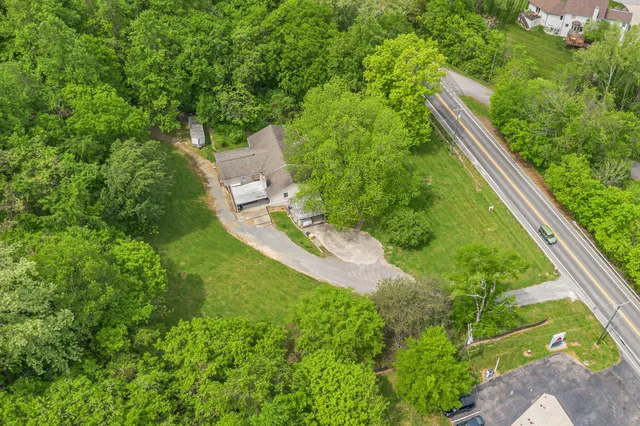 an aerial view of residential house with outdoor space and trees all around